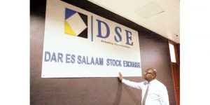 A man stands by the billboard of the Dar es Salaam Stock