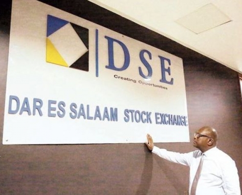 A man stands by the billboard of the Dar es Salaam Stock